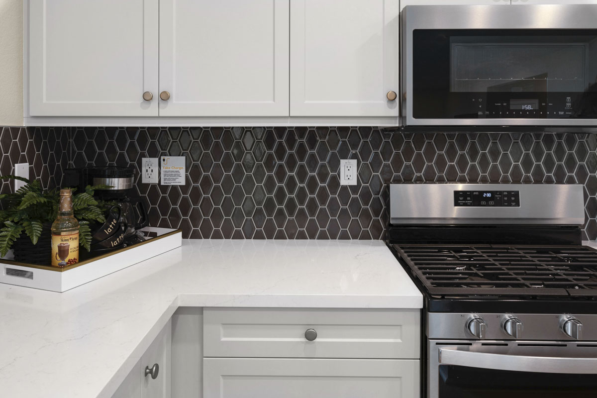 Upgraded quartz countertops with custom tile backsplash at kitchen