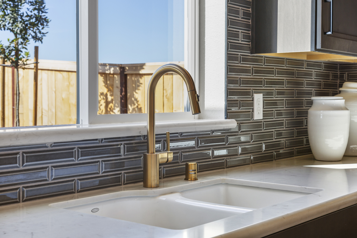 Gold faucet and decorative kitchen backsplash
