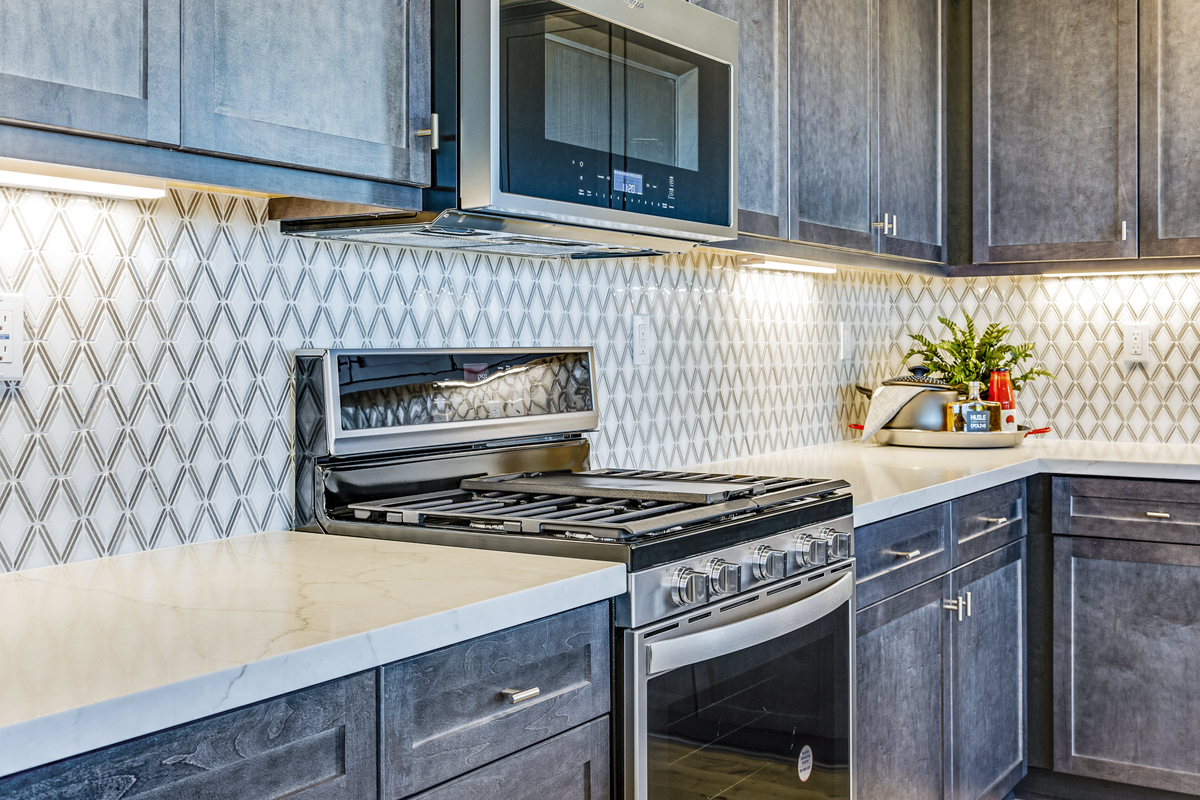 Upgraded quartz countertops with custom tile backsplash at kitchen