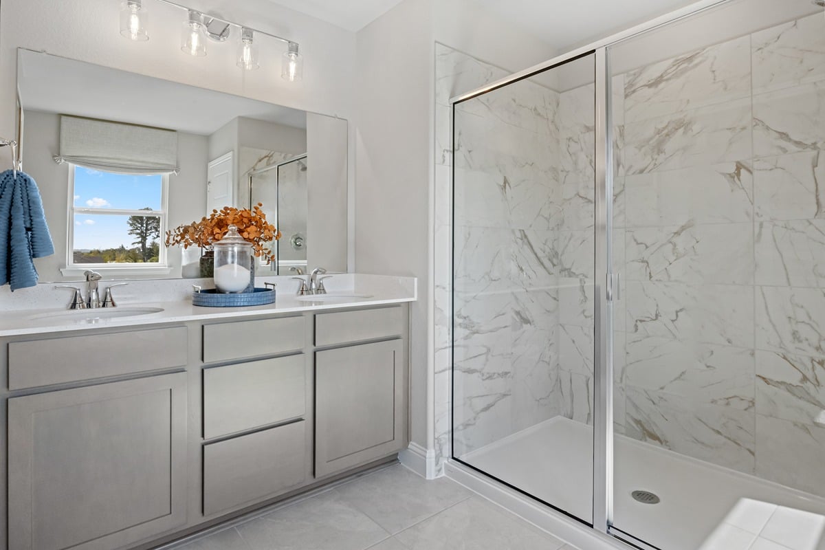Walk-in shower with decorative tile surround at primary bath