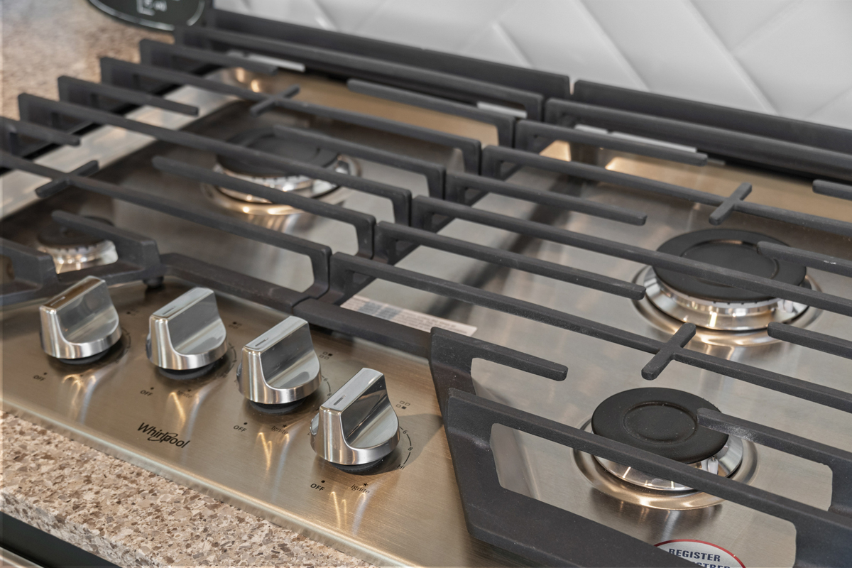 Gas cooktop with hinged cast-iron grates
